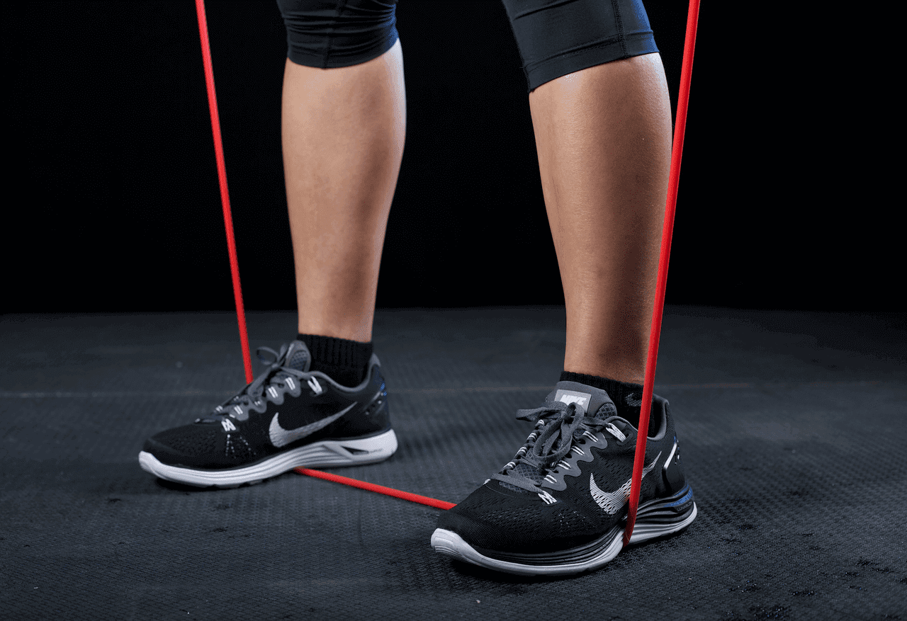 Person performing xbar workouts with resistance bands on the floor for full-body training.