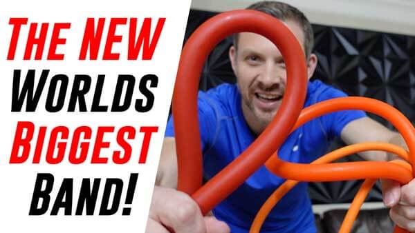 Person holding a large extra heavy red resistance band with text 'The New World's Biggest Band' on the left.