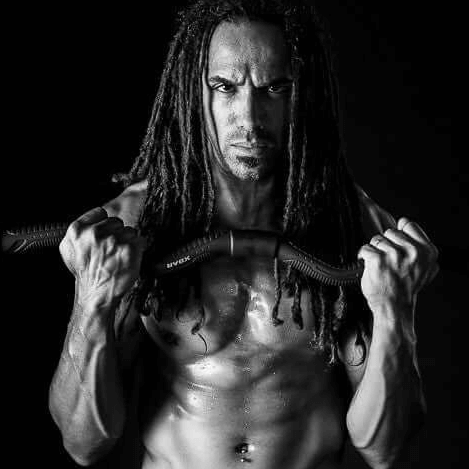 Brian Marshall holding xbar fitness curl bar against a black bakground