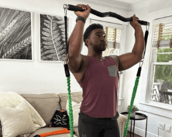 Man exercising with resistance bands in a living room.