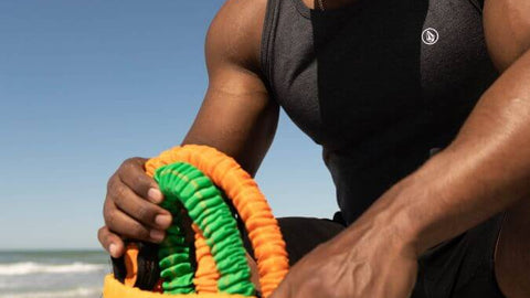 Man packing green and orange resistance bands in his travel accessory bag.