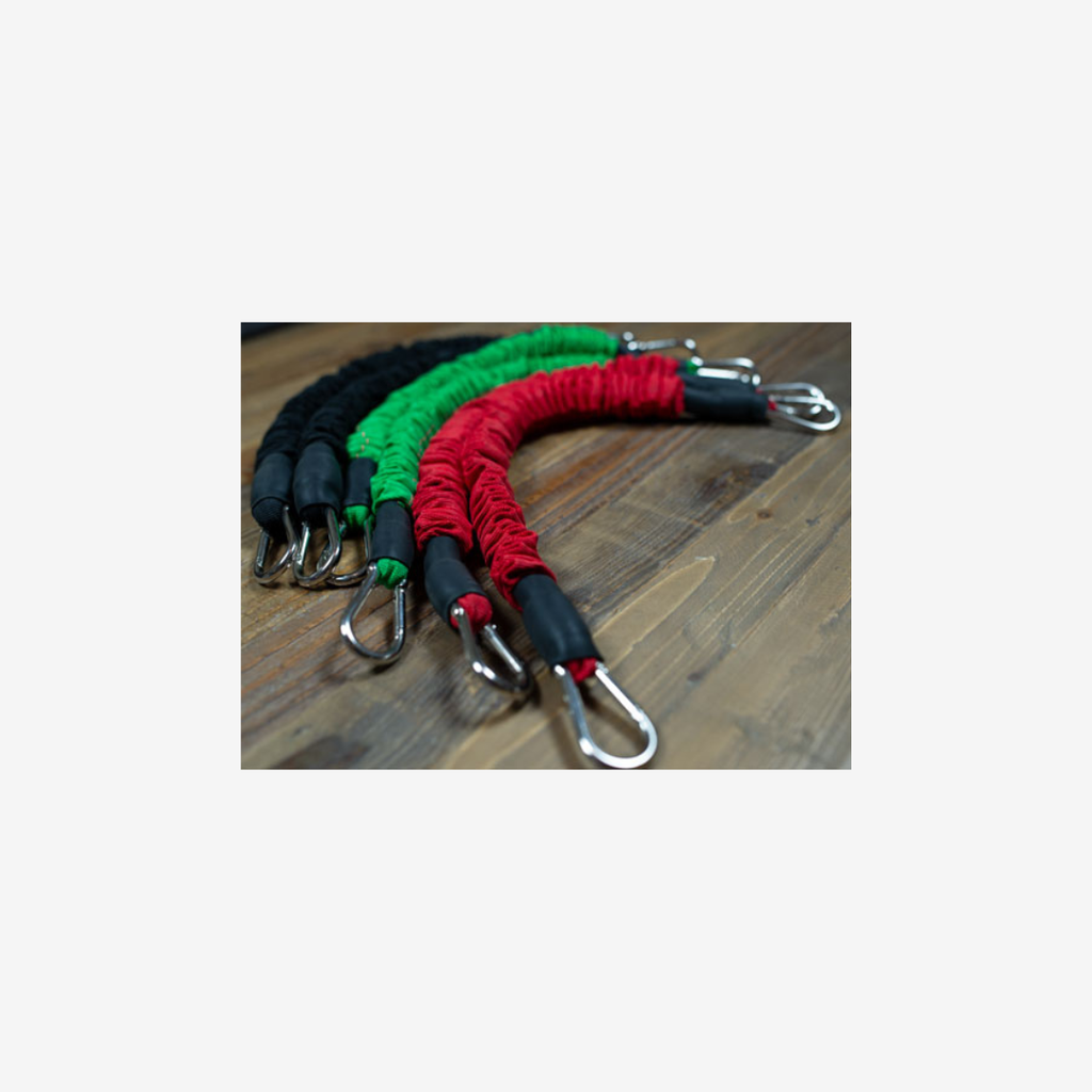 Set of three resistance bands in red, green, and black on a wooden surface