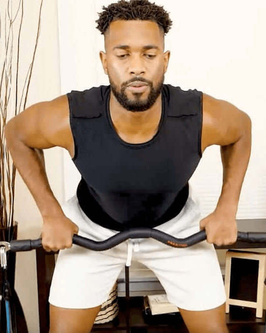 Man exercising with medium resistance band single with xbar exercise bar fitness system in a living room.