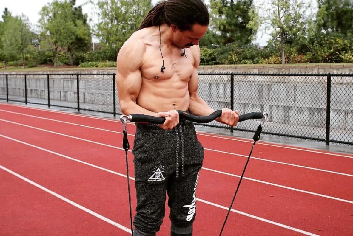 Athlete performing biceps curls with the XBAR resistance training system on an outdoor track