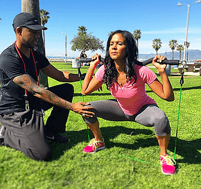 Woman doing squats with trainer, XBar fitness gallery