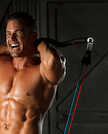 Muscular man exercising with resistance bands in a dark setting